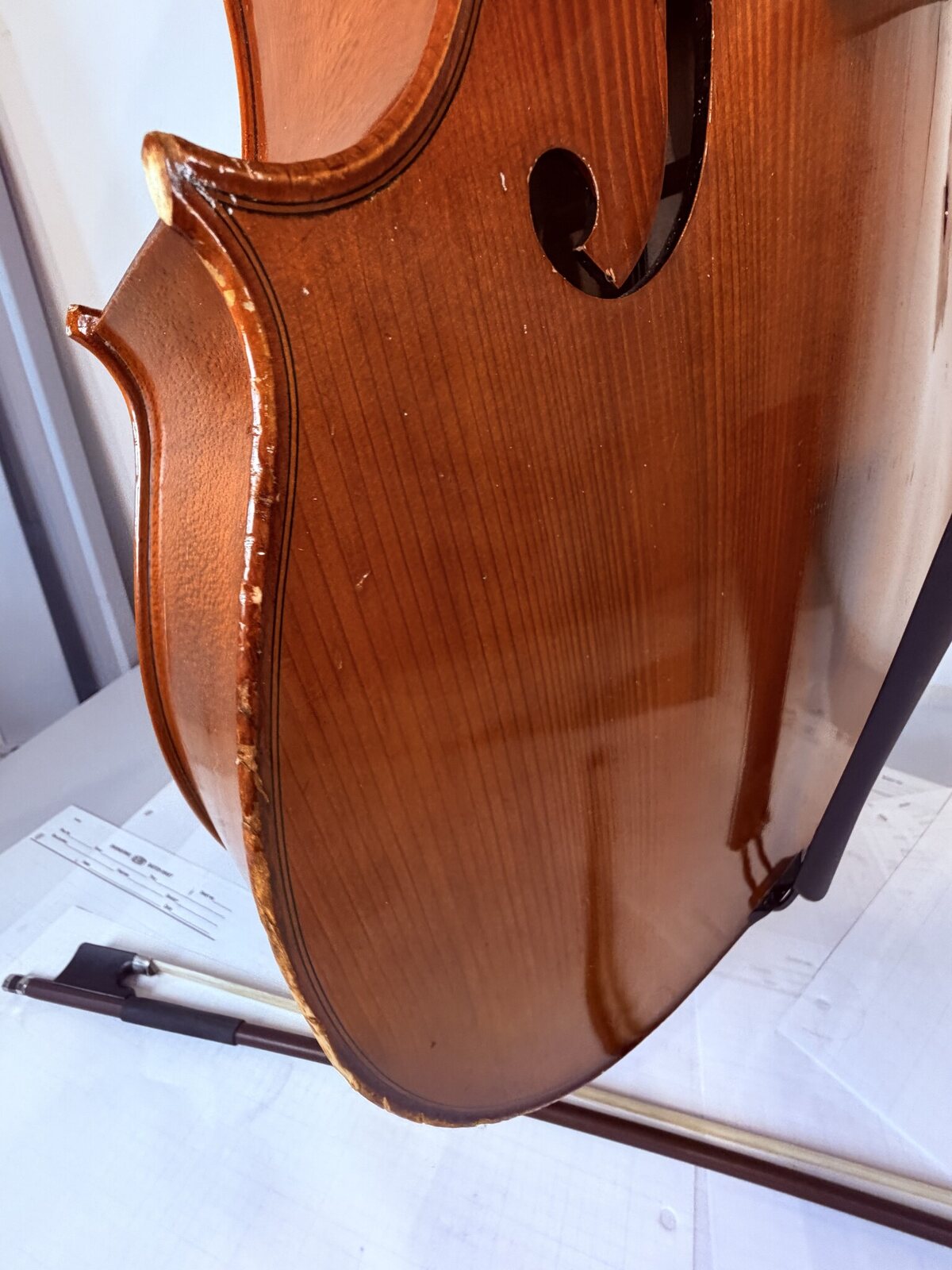 Open top-to-rib seam on the cello with bare wood visible along the purfling line